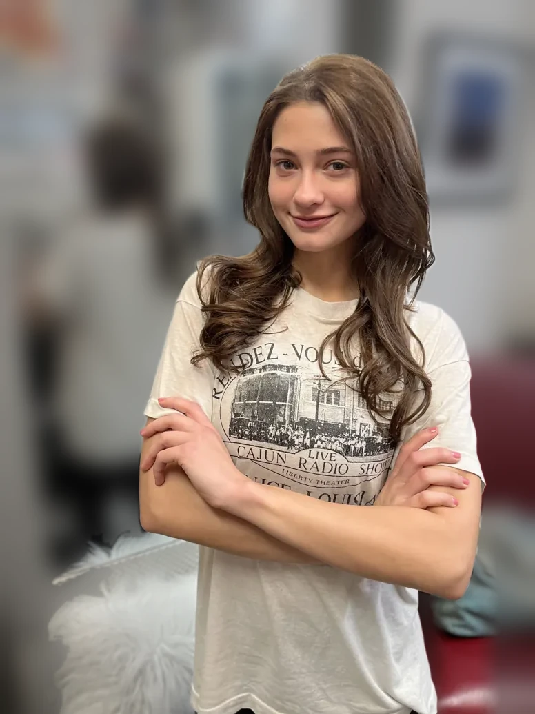 Smiling client with fresh brunette waves, arms crossed