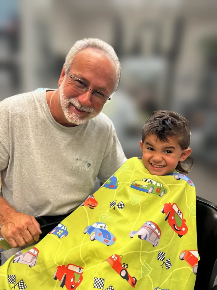 Grandpa and grandson grinning together after their haircuts