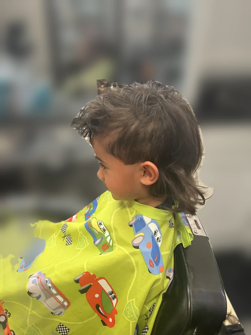 Little boy rocking a fresh mullet in a race car cape