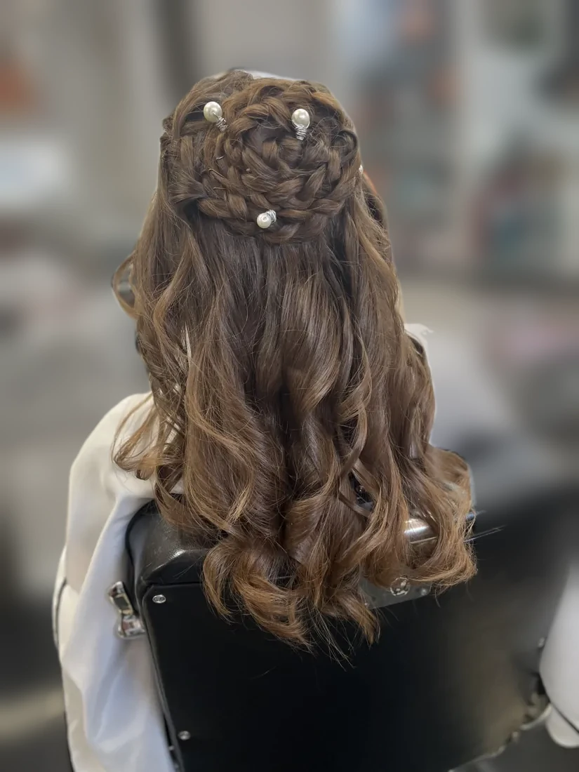 Braided rose bun dotted with pearl pins above loose curls