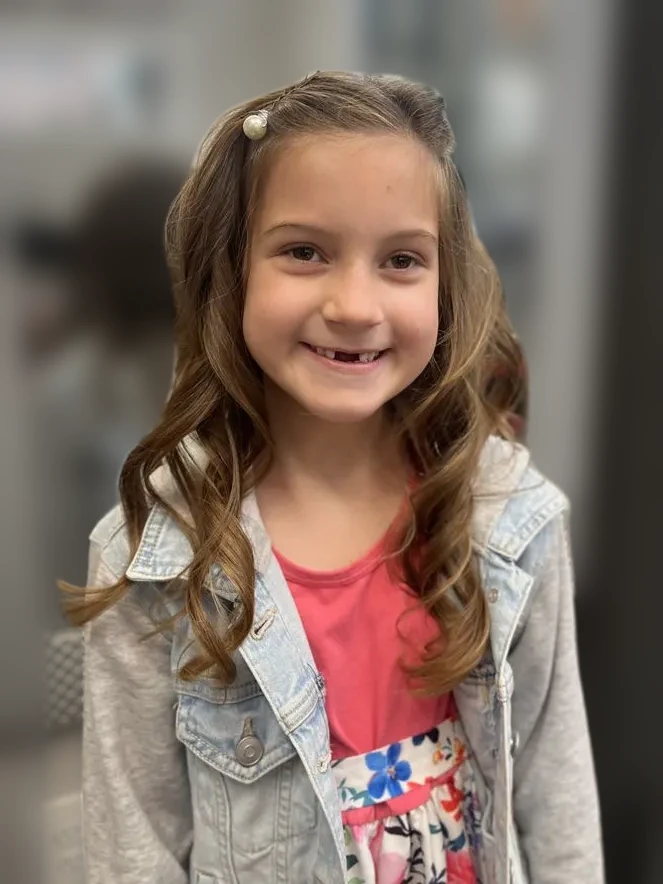Little girl smiling with soft curls and a pearl clip